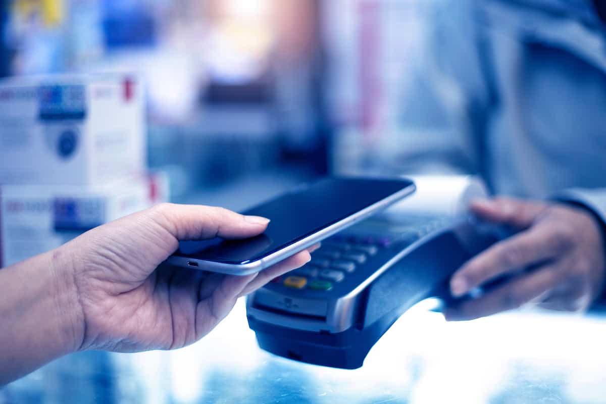 A consumer uses their mobile device up against a card reader in order to pay for their coffee in a cafe