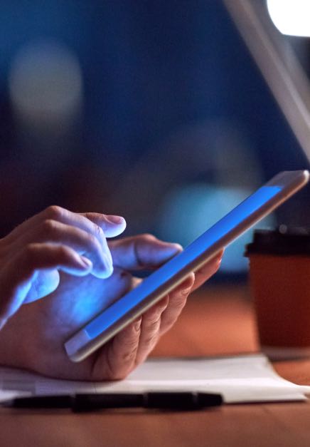 Person types on a tablet in a dark room