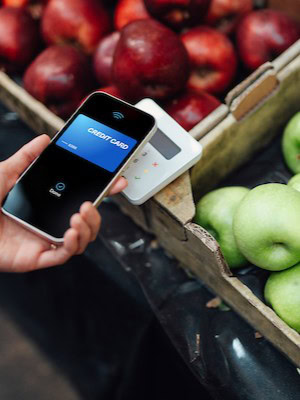 Contactless payment, credit card, smartphone, fruit market, digital transaction.