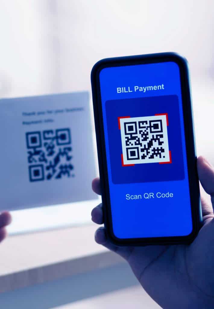 A person uses their phone to scan a QR code to pay their bill.