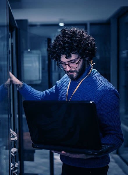 Man standing, holding a laptop