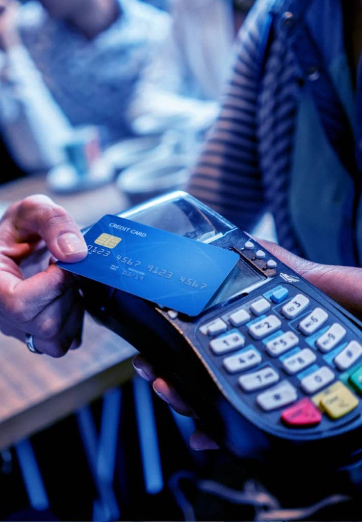 A person tapping a credit card onto a card reader in a store
