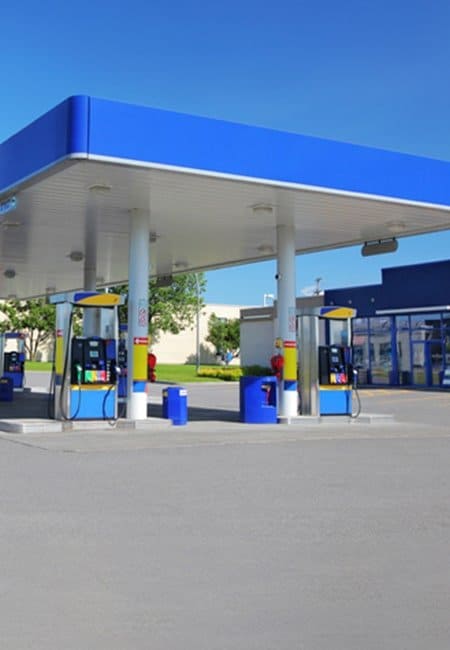 Gas station pumps and convenient store from entrance of gas station parking lot