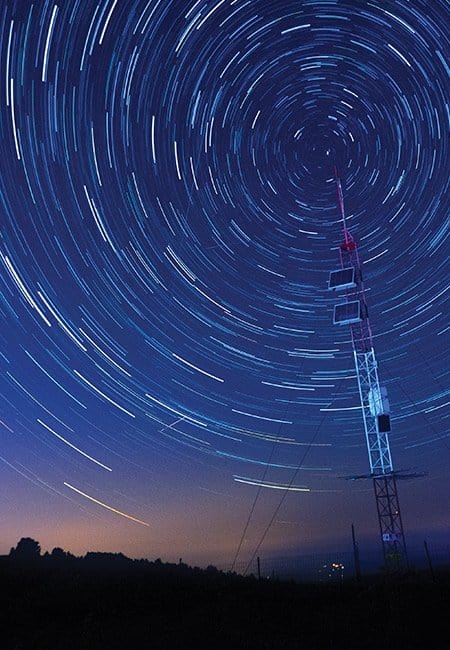 Cell tower at dusk with circular light motion blur