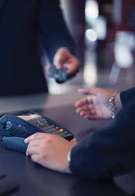 A man hands his credit card to a woman so that she can finish his transaction at a hotel. 