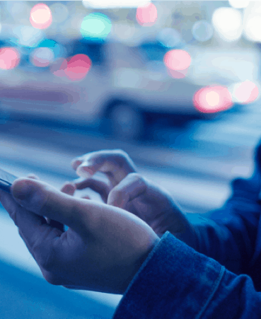 Person holding their smartphone while a car drives by in motion blur in the background