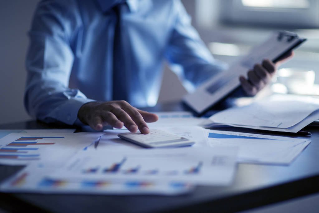 Business accounting concept, Business man using calculator with , budget and loan papers in his office.