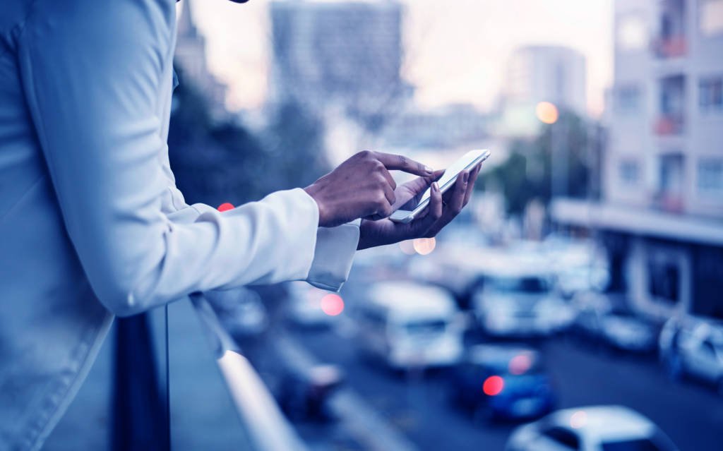 Cropped shot of a businesswoman using a smartphone out on the balcony of a modern office