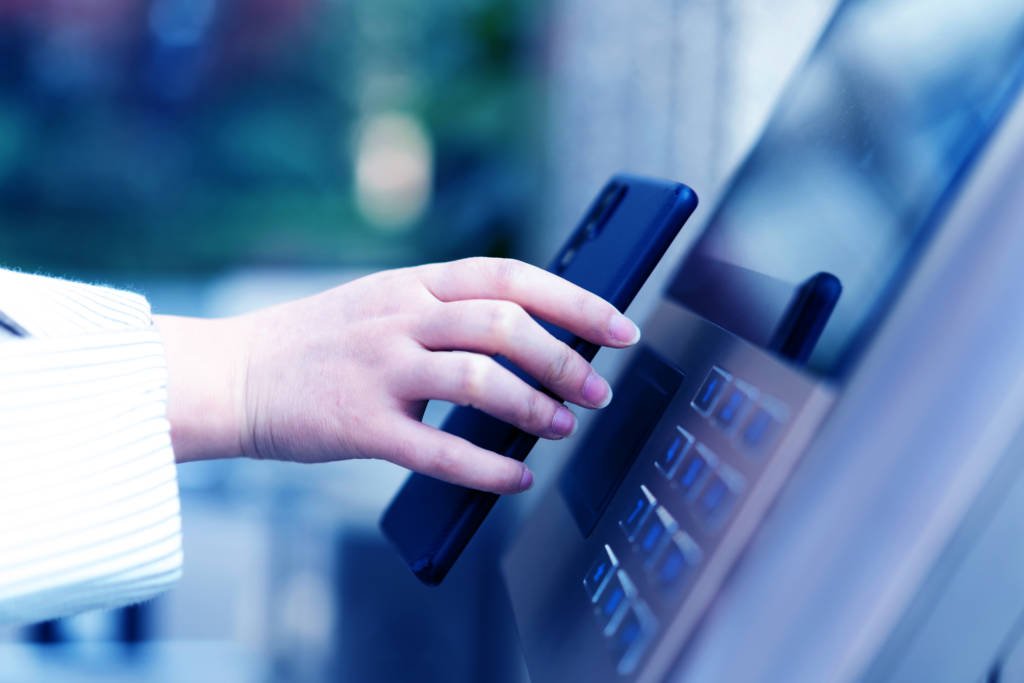 A woman uses her phone at an ATM for wireless processing