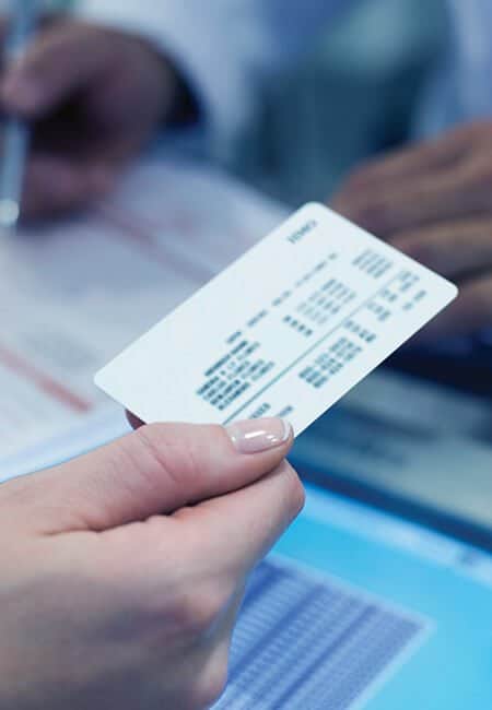 A person hands over their insurance card to a healthcare professional.