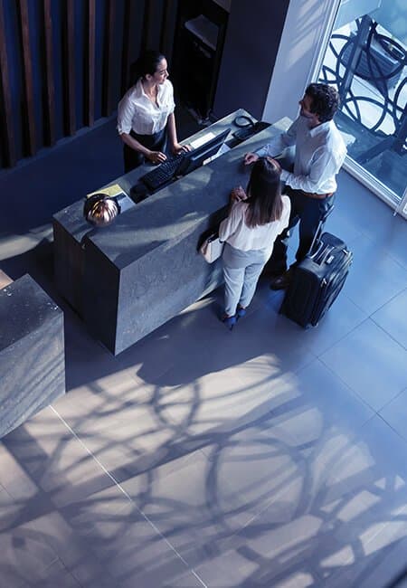 A view of a couple from above checking in to a hotel at the front desk.