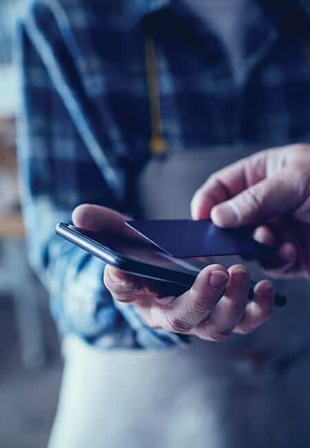 A person tapping their credit card to a merchants smartphone