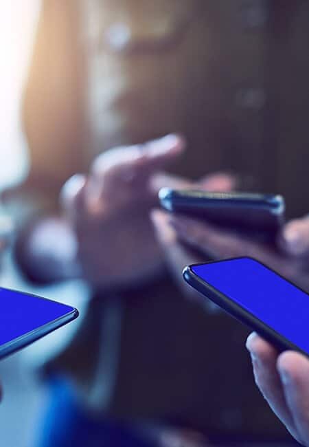 Three blurred people each holding their smartphones