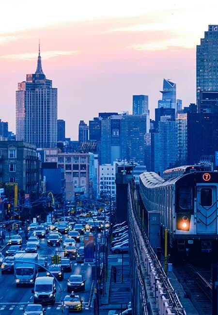 City scape at sunset from the train tracks with train coming and traffic below