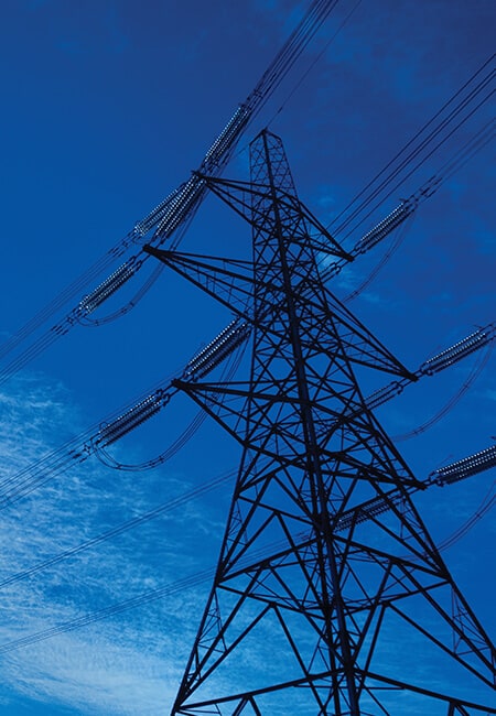 Upward shot of an electrical tower with power lines leading to and away from it.