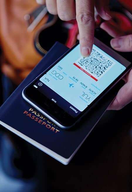 Person looking at boarding pass on their smartphone on top of their passport. All of which is in their hand.