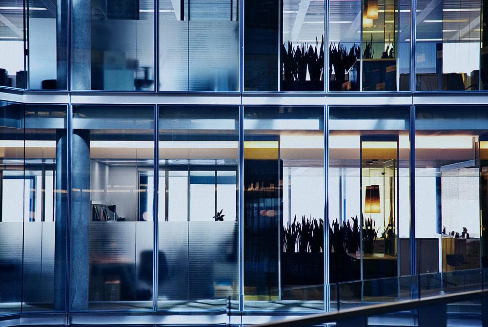 Modern office building with glass facade reflecting cityscape.