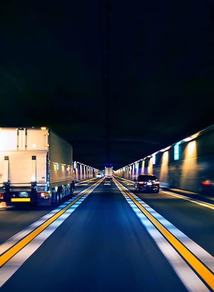A three lane highway at night, there is blurring around the edges due to the fast speed of both the photographer and the environment surrounding them.