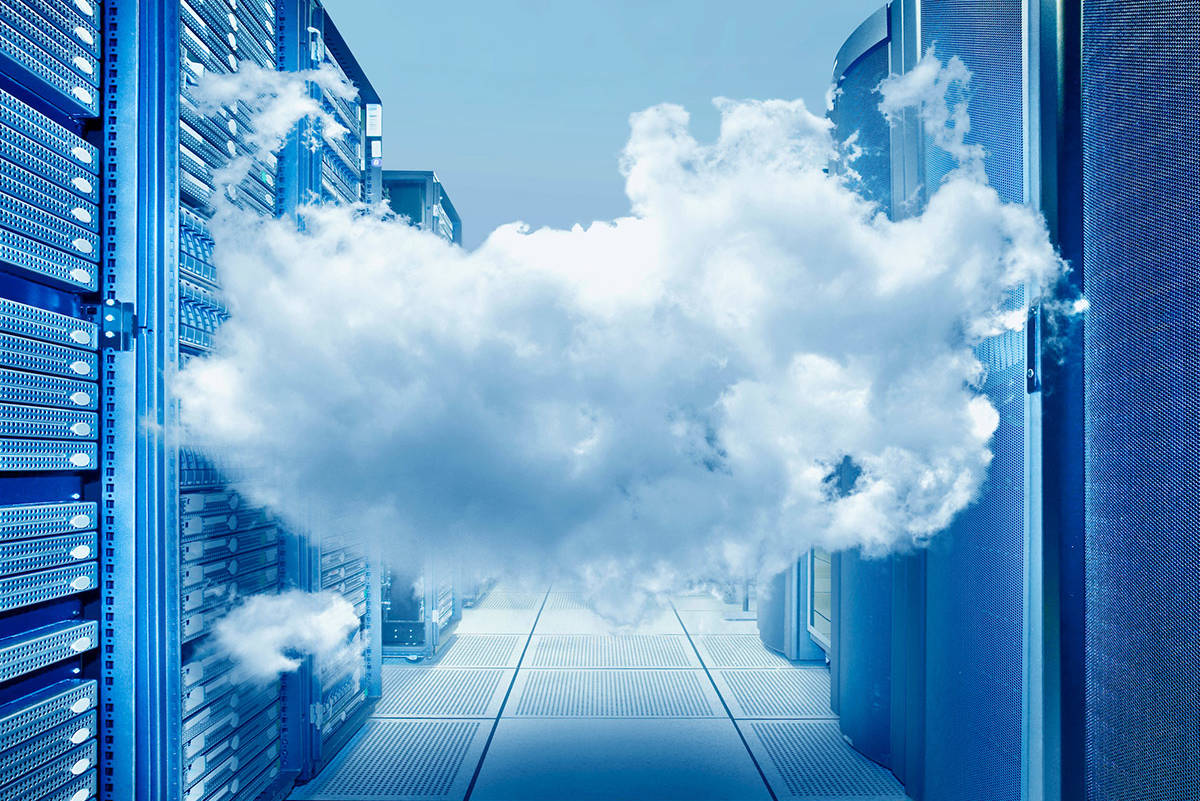 A cloud floats between two walls of servers. A way of showing the idea of what cloud computing is.