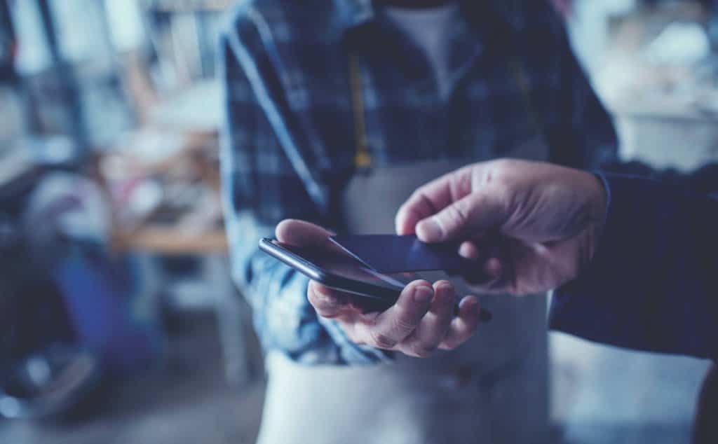 A person pays the merchants with their credit card through the merchants smartphone