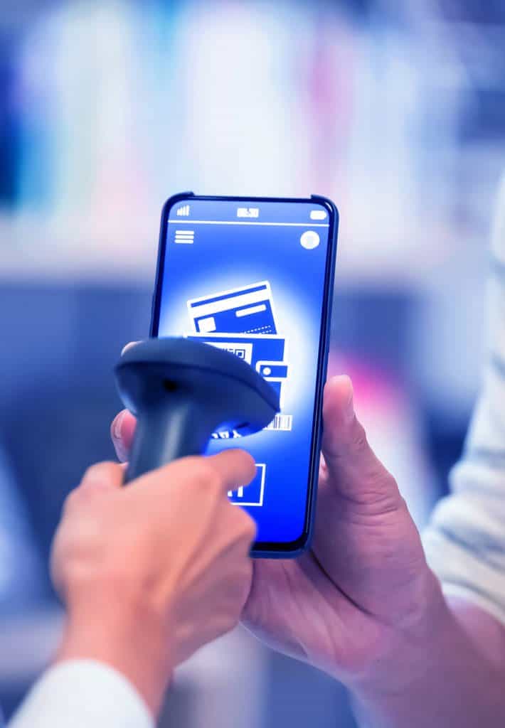 A cashier scans a coupon or membership card on a customers smartphone screen.
