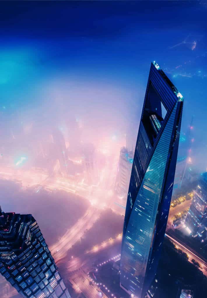 An aerial view of a city on a foggy night, the street lights and cars can just be seen through the fog.