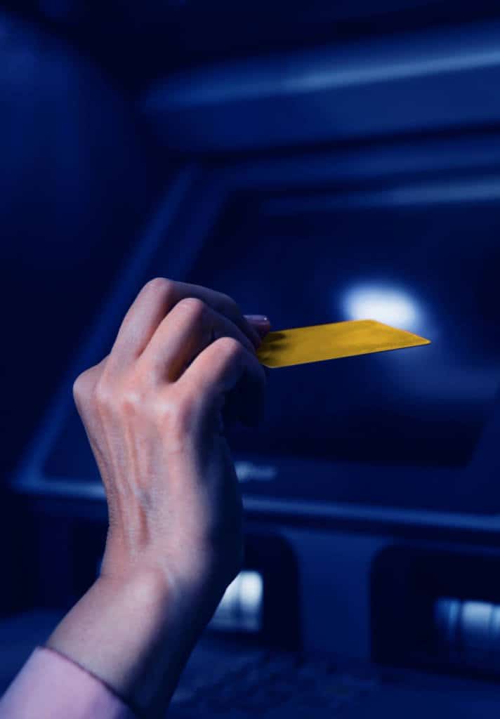 A person holding up a gold credit card with a dark background