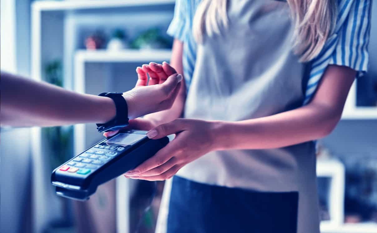 A person using their apple watch on a card reader to pay at a store