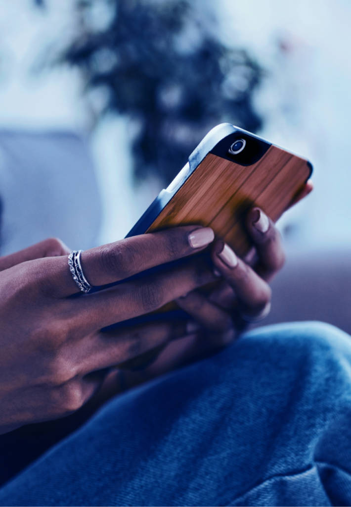 A woman is on her smartphone which has a wood textured case