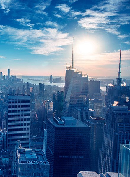 City view from top of a building with the sun shining from a blue sky