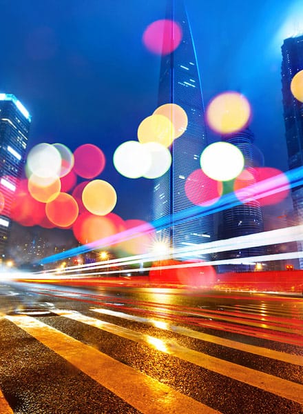 Ground level from roadway looking up at skyscrapers with red, white and yellow light reflective circles