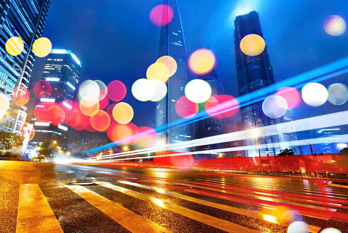 Ground level from roadway looking up at skyscrapers with red, white and yellow light reflective circles