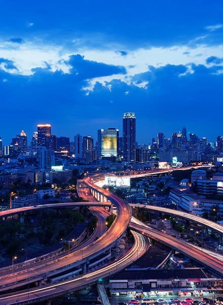 Cloudy night skyline of city with roads in front of it