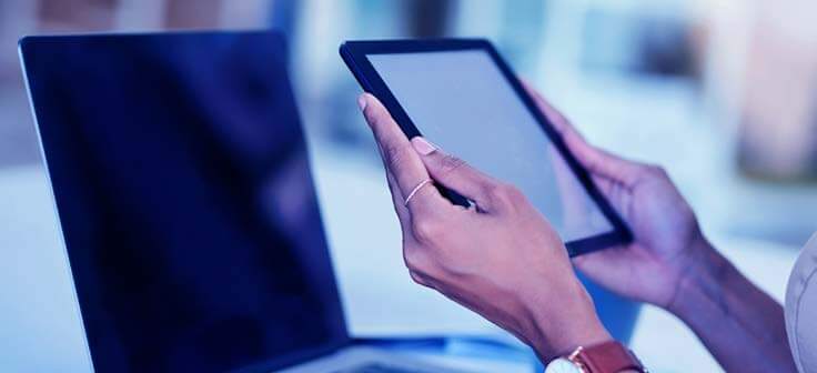 Woman outside on her tablet with her sleeping laptop behind her