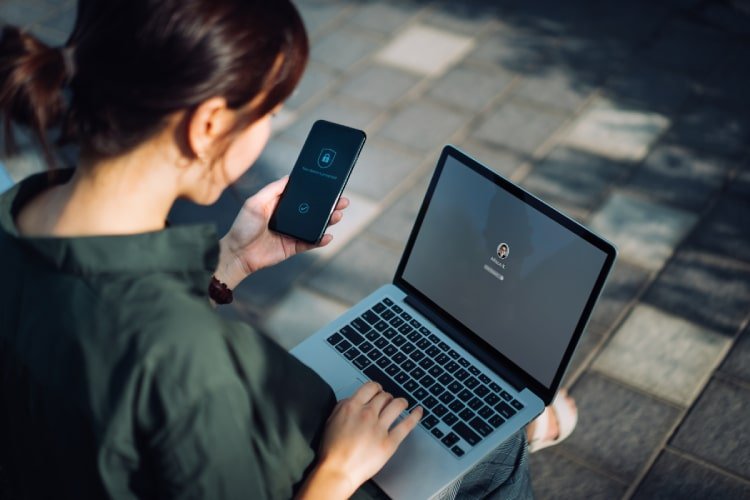 Women verifying security settings on mobile phone and laptop