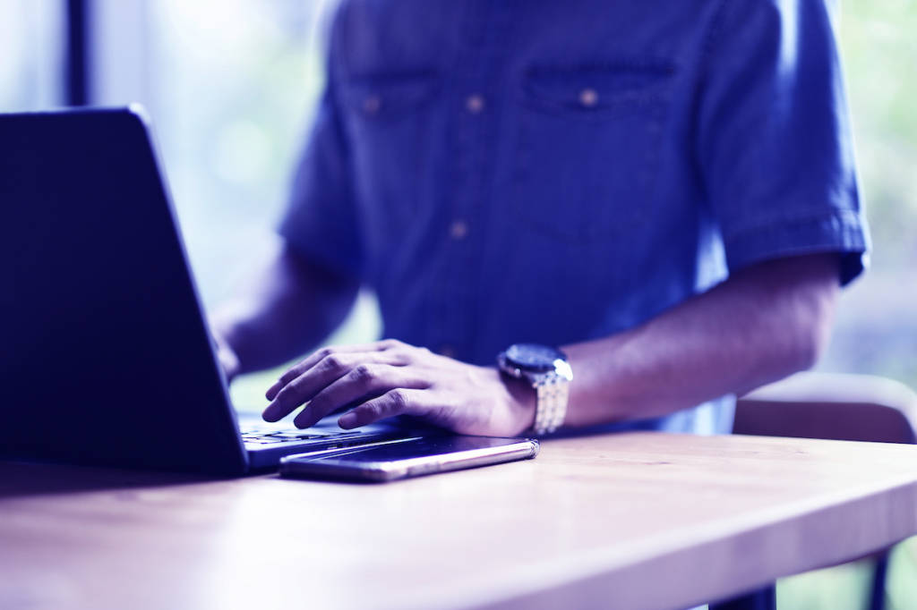 Hands working on a laptop in an office