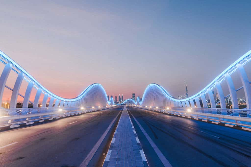A night time view of the illuminated Meydan Bridge just outside Dubai city