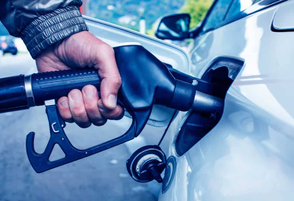 Mans's hand holding fuel nozzle in car