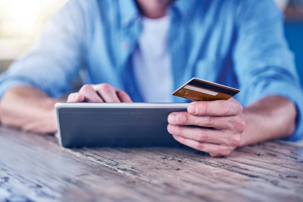 Person holding a credit card and using a tablet for payment.