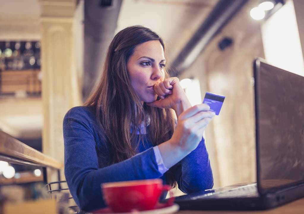 Businesswoman using a credit card on her laptop in a cafe setting.