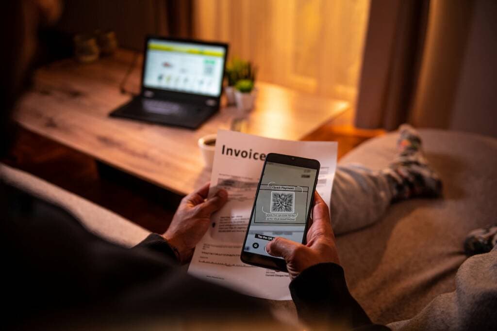 Person scanning QR code on invoice with smartphone in home setting.
